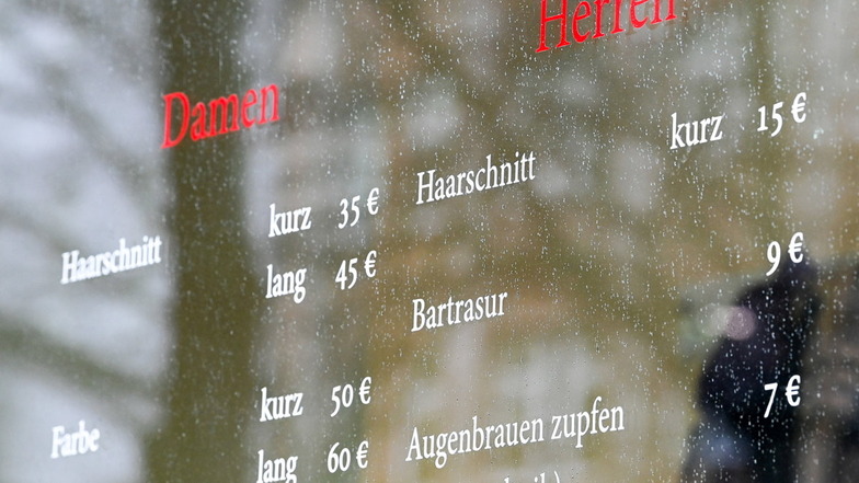 Unterschiedliche Preise für Damen- und Herrenhaarschnitte sind an einer Fensterscheibe eines Friseursalons in Berlin zu sehen.