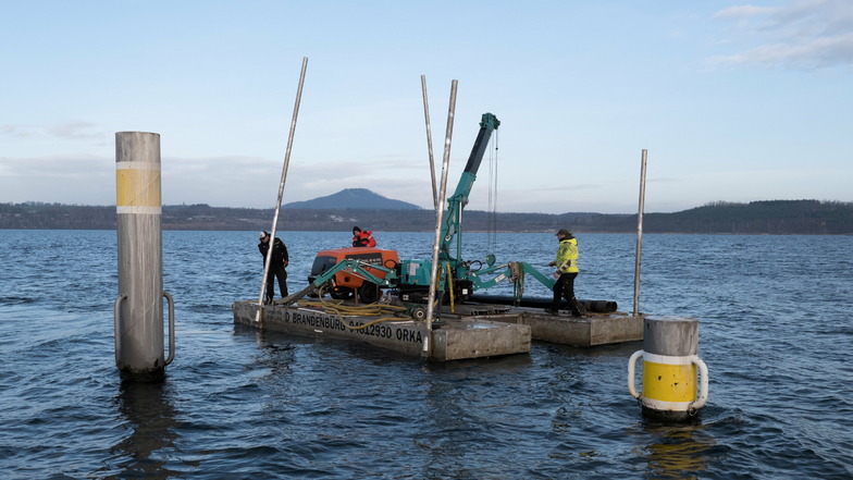 Das Team der Firma Orka Steganlagen ist mit der Arbeitsplattform auf dem Berzdorfer See. Es rammt Rohre in den Seeboden - bei Wind und Wetter.