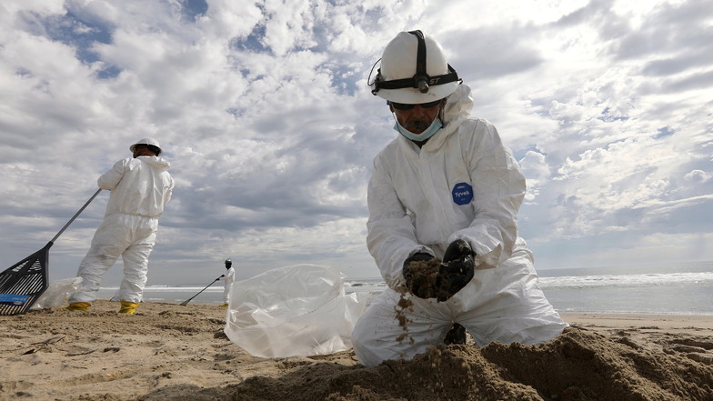Mitglieder des Aufräumteams sammeln am Huntington Beach in Orange County, Kalifornien, Öl aus dem Sand.