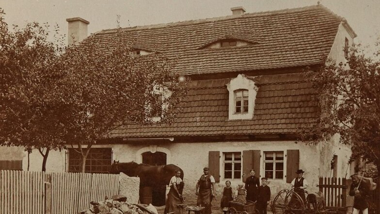 Das mehr als hundert Jahre alte Foto von der Ursprungsschmiede hängt noch heute in der guten Stube: Das Haus wurde 1979 abgerissen und auf dessen Grundmauern ein Wohnhaus errichtet. Die Schmiede war bereits 1939 in einen Neubau nur wenige Meter weiter gez