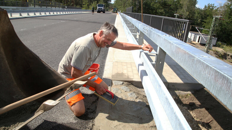 Bis zur Freigabe der B 115-Brücke am Freitag bleibt noch ein wenig Arbeit. Roland Hänel, Polier bei der Bautzener Firma Hentschke-Bau, kümmert sich um das Verfugen des Raubettes für die Straßenentwässerung.