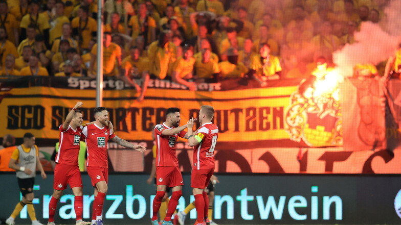 Der Anfang vom Ende: Die Spieler von Kaiserslautern jubeln nach dem Treffer zum 0:1, im Hintergrund zünden Dynamo-Fans bengalische Feuer.