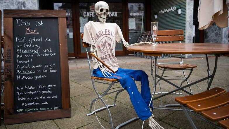 Ein Skelett sitzt Anfang März mit einem leeren Bierglas vor einem wegen der Corona-Pandemie geschlossenen Restaurant Hannover.