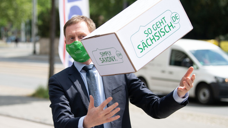 Michael Kretschmer übergibt 1.000 Schutzmasken mit dem "So geht sächsisch."-Aufdruck der Kampagne des Freistaates an einen Supermarkt in Dresden.