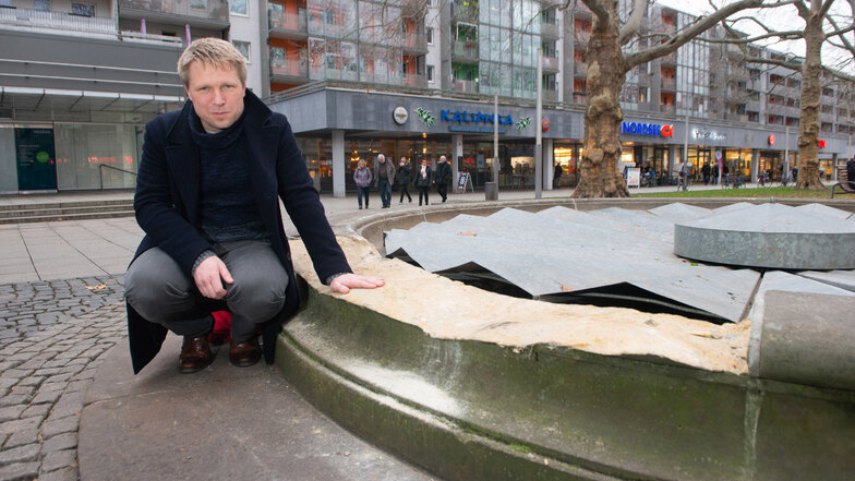 Anwohner Jörg Götte an dem beschädigten Brunnen auf der Dresdner Hauptstraße. Der Aufwand wird erheblich, das zerstörte halbrunde Sandsteinteil wieder zu ersetzen.
