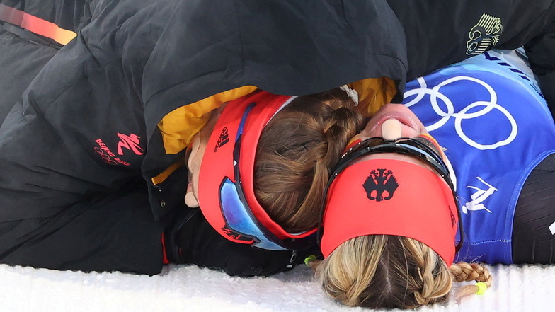Erschöpft, aber glücklich liegt sich das Duo im Schnee in den Armen.