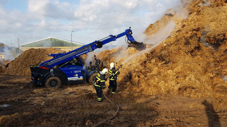 Auch am Vormittag laufen die Löscharbeiten des Strohlagers in Berbersdorf. Das THW unterstützt die Feuerwehr mit Teleskop- und Radladern.