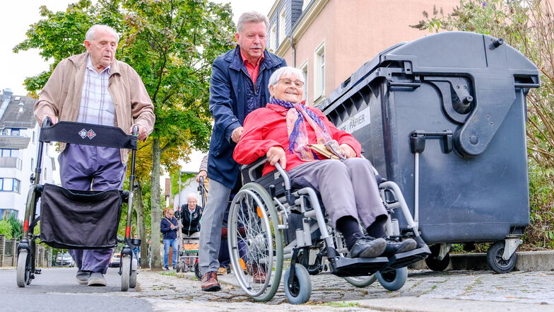 Beim Spaziergang packte OB Bert Wendsche mit an und schob eine Frau im Rollstuhl. Nicht nur Pflastersteine stellen eine Herausforderung dar. Auch Mülltonnen blockieren den Weg, sodass der Mann mit dem Rollator auf die Straße ausweichen muss.