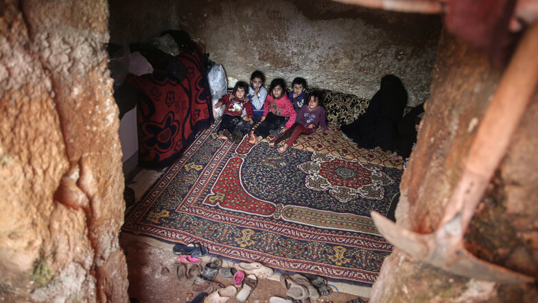 Syrien, Taltuna: Syrische Kinder sitzen in einer Höhle auf einem Teppich. Mindestens acht Familien leben dort zusammen, nachdem sie von syrischen Regierungstruppen aus Aleppo vertrieben wurden.