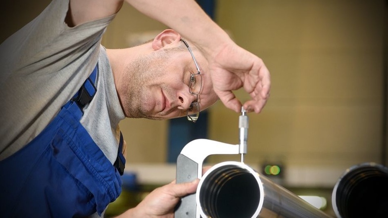 CNC-Dreher Rico Kaiser bei einer Kontrollmessung für ein Zylinderrohr.
