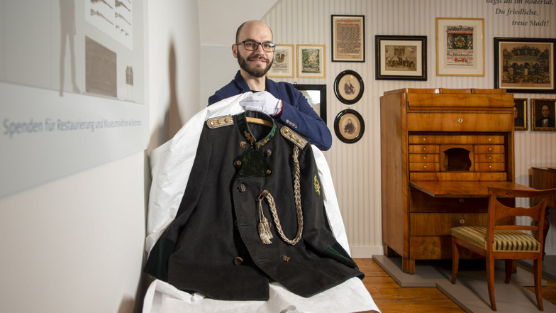 Robert Rösler, Leiter des Heimatmuseums Radeburg, mit einer im Vorjahr restaurierten Schützenuniform. An der derzeit noch freien Wand sollen künftig Objekte aus der umfangreichen Waffensammlung des Museums präsentiert werden.
