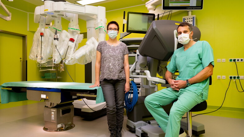 Christine Krahl steht mit Marius Distler, stellvertretender Direktor der Klinik für Viszeral-, Thorax- und Gefäßchirurgie des Uniklinikums Dresden, vor dem Da-Vinci-Roboter, mit dem sie operiert wurde.