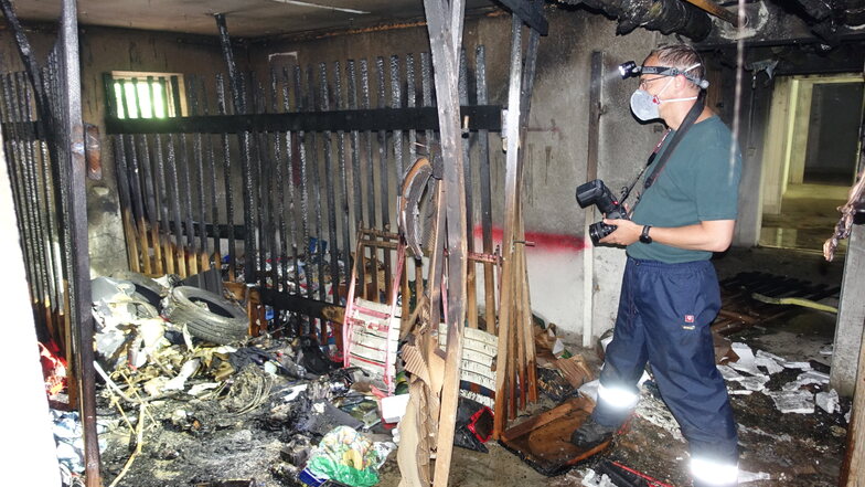 Ein Brandursachenermittler der Polizei macht im ausgebrannten Keller des Hauses Straße der Jugend 1 in Döbeln Nord Fotos.