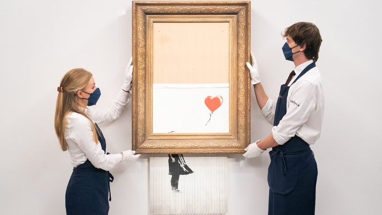 Kunsthändler halten das Bansky-Werk "Love Is In The Bin". Ursprünglich "Girl With Balloon" genannt, wurde es 2018 während einer Auktion von Banksy teilweise geschreddert. Der Künstler benannte sein berühmtes Bild danach um.