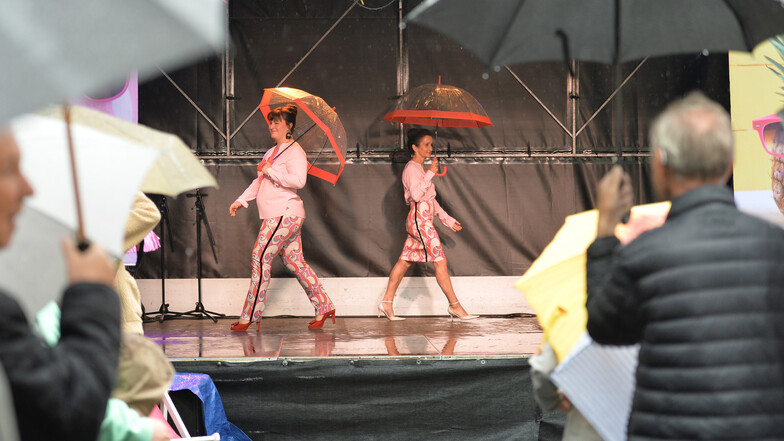 Modenschau auf dem Straßenfest „Radebeul tanzt“. Auch mit Regenschirm versprühen Pia und Gudrun Ast einen Hauch von Sommer beim Präsentieren der Sommerkollektion der Marke Herzensangelegenheit.
