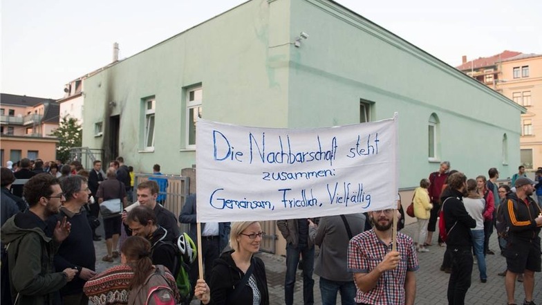 Teilnehmer halten vor der Fatih Camii Moschee in Dresden ein Transparent in die Höhe. Darauf steht: "Die Nachbarschaft steht zusammen: Gemeinsam, Friedlich, Vielfälig".