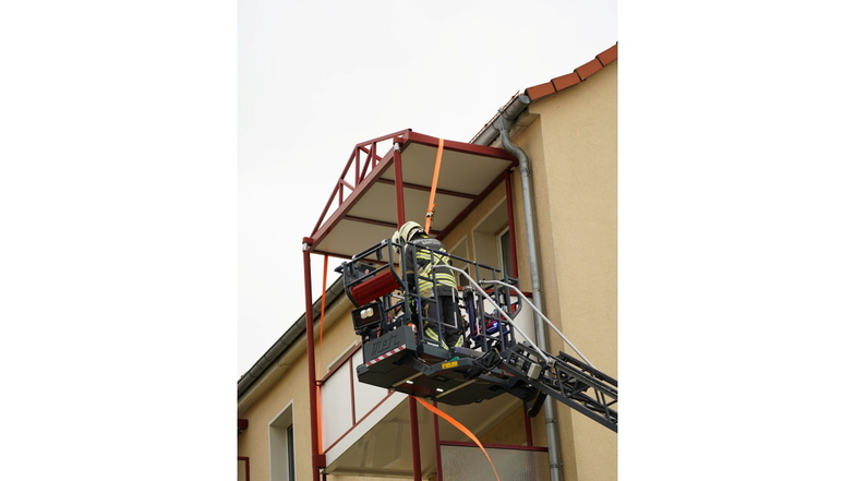 Bei einem Mehrfamilienhaus an der Berthold-Brecht-Straße in Bautzen hatte sich das Dach eines Balkons gelöst. Feuerwehrleute befestigten es behelfsmäßig.