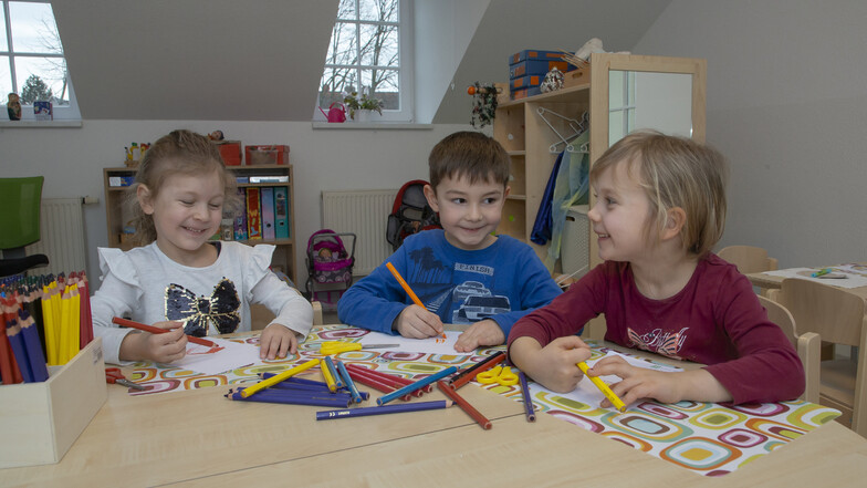 Lotta (4, links), Marlo (5) und Elise (5) basteln und malen im neuen Gruppenzimmer im Dachgeschoss des Kindergartens Zwergenland am Wilischrand in Kreischa.