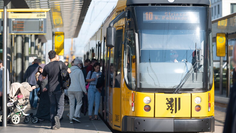 Frau läuft an Dresdner Haltestelle vor Straßenbahn