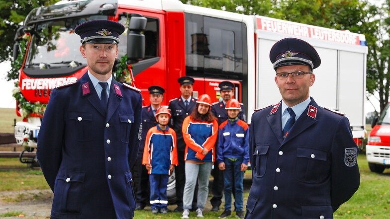 Steffen Fiedler (rechts), Tobias Zschierlich und Leutersdorfer Feuerwehrleute zeigen das neue Löschfahrzeug der Wehr.