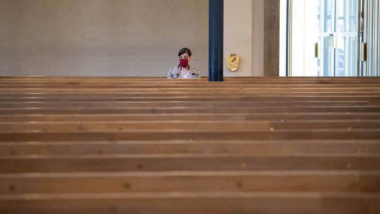 Bayern, München: Eine Frau mit Mundschutz verfolgt einen Gottesdienst in der ansonsten fast menschenleeren St. Matthäuskirche. Aufgrund der Corona-Krise wurde der evangelische Gottesdienst ausschließlich im Radio und Internet übertragen.