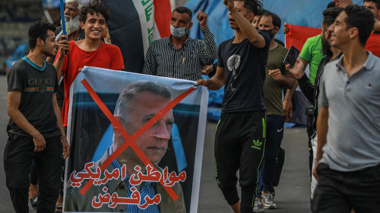 Teilnehmer eines regierungskritischen Protests halten ein Plakat mit einem durchgestrichenen Foto des derzeitigen Chefs des irakischen Geheimdienstes, al-Kasimi.