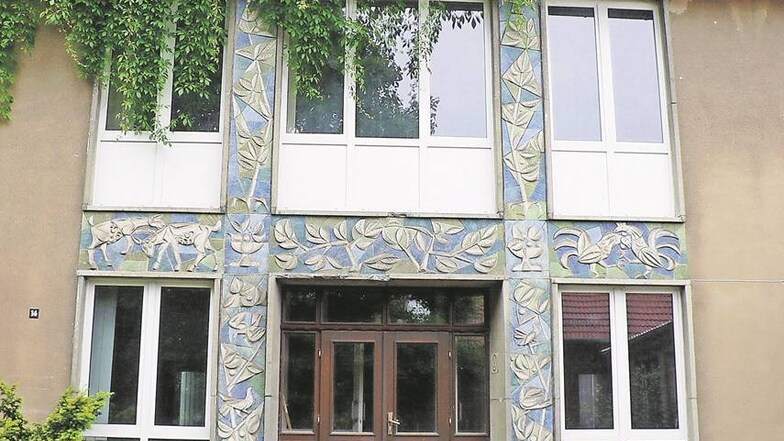 Der Eingangsbereich macht die alte Berufsschule Langenhennersdorf zum kulturhistorischen Denkmal. Die Ornamente an der 1957 gebauten Schule stammen von Willi Sittes Bruder Rudolf Sitte. Das schmucke Portal hat der Schule nicht geholfen, der Eingang wächst