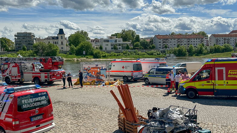 Einsatzfahrzeuge stehen am Elbufer in Magdeburg: Mehrere Kinder sind am Sonntag verletzt worden, als bei einer Veranstaltung eine Hüpfburg von einer Windböe erfasst und in die Elbe geweht wurde.