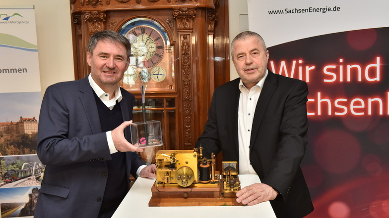 Landrat Michael Geisler (CDU) und Jens Schaller, Geschäftsführer von Sachsen-Gigabit, unterzeichnen vor einem Morseapparat und modernem Lichtleitkabel den Kooperationsvertrag.