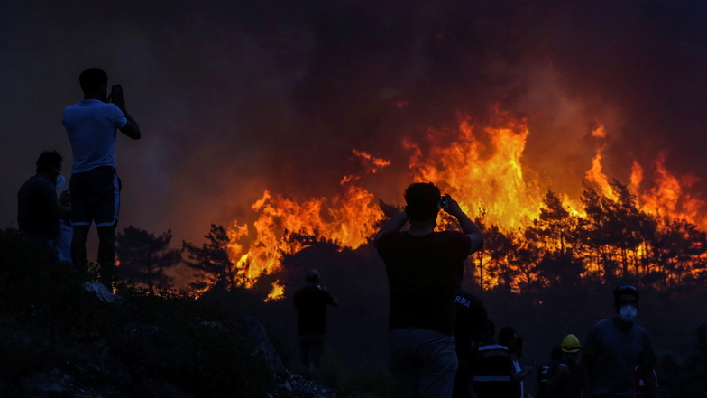 Türkei, Milas: Anwohner beobachten einen Waldbrand in der Nähe des Dorfes Akcayaka. In der Türkei sind weiterhin große Brände außer Kontrolle.