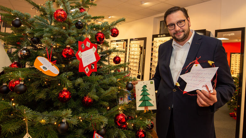 Mathias Lange von Pro Optik zeigt die Kinder-Wunschzettel am Baum in seinem Geschäft.