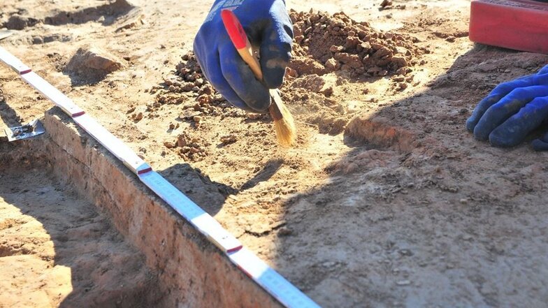 Mit einem Pinsel legen die Archäologen bestimmte Überreste der Siedlung frei.