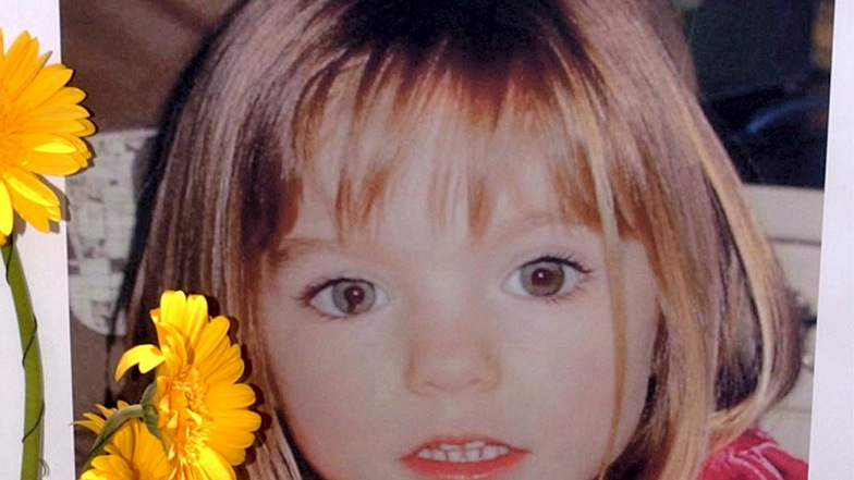 Blumen stehen vor einem Bild, das die verschwundenen Madeleine McCann (Maddie) auf einem Foto zeigt, das ihre Eltern 2007 im Zusammenhang mit dem Verschwinden des Kindes veröffentlich haben.