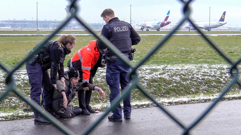 Zwei Beamte der Bundespolizei und ein Sicherheitsmitarbeiter entfernen einen Protestler vom Gelände des Airports in Berlin.