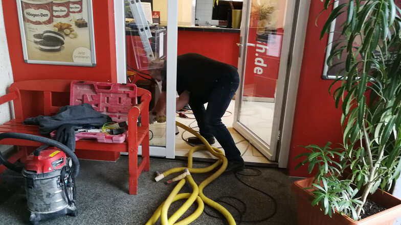 Ein Mitarbeiter einer Firma für Brand- und Wasserschadensanierung schließt einen Schlauch an ein Trocknungsgerät an.