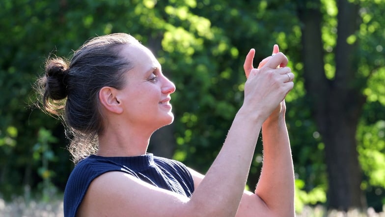 Sara Engelmann, Organisatorin des Meißner Kultursommers, macht ein Handy-Foto im Park des Katharinenhofs.