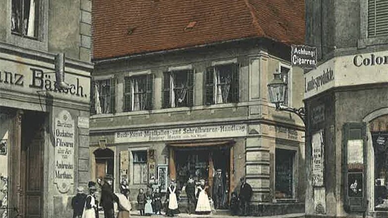 Berliner Straße 1 und 2:  Die Karte von 1910 zeigt die Schuhhandlung Bänsch mit dem Stiefel an der Fassade, den Colonialwarenladen Ecke Kirchplatz und die Buchhandlung Alferie (Mitte).