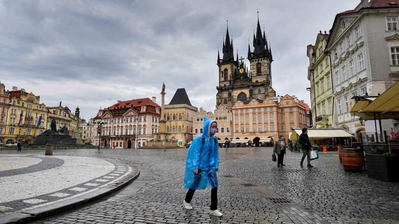 Eine Frau geht bei Regen durch die fast menschenleere Altstadt. Die Tschechische Regierung hat ihre Corona-Regeln stark verschärft.