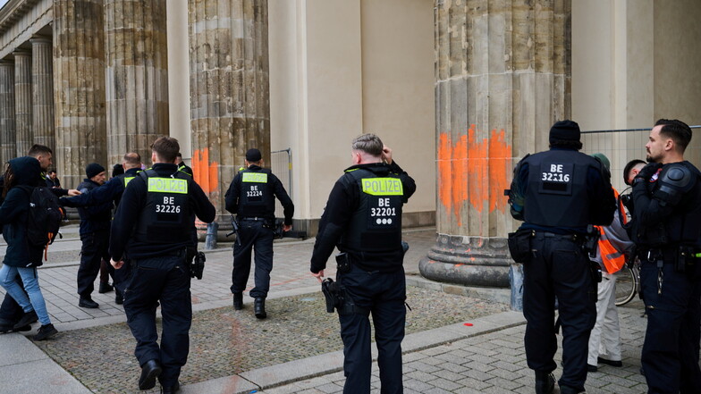 Polizeibeamte nehmen zwei Klimaaktivistinnen in Gewahrsam, die das Brandenburger Tor mit oranger Farbe bemalt haben.