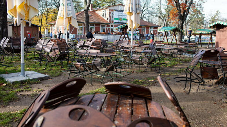 Die zusammengeklappten Stühle lehnen an den leeren Tischen im Biergarten.