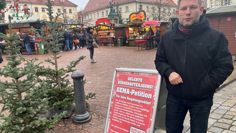 Kulturkoordinator Jörg Withulz zeigt auf dem Großenhainer Weihnachtsmarkt den Aufsteller zur Bürgerbeteiligung im Landkreis Meißen.