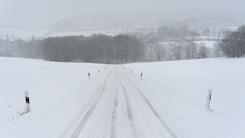 Eine Fahrspur zieht sich durch eine verschneite Straße im Erzgebirge.