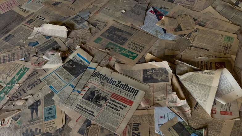 In einem Raum liegen ein kleines Zeitungsarchiv auf dem Boden.