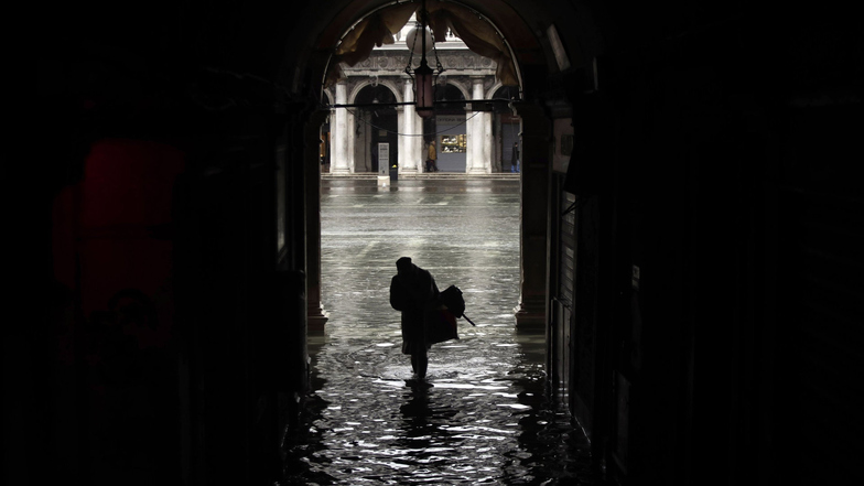 Eine Frau watet über den überfluteten Markusplatz. 