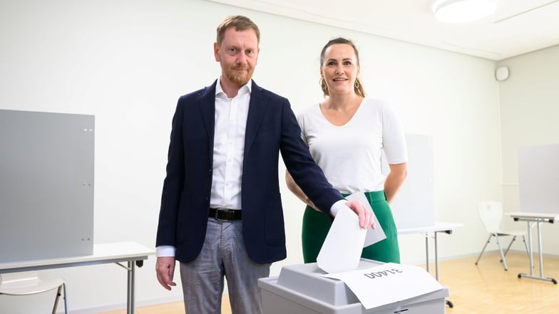 Michael Kretschmer (CDU), Ministerpräsident von Sachsen, steht mit seiner Frau Annett Hofmann bei der Stimmabgabe in einem Dresdner Wahllokal an einer Wahlurne.