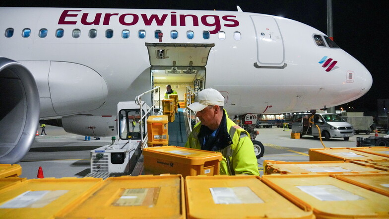 Ein Airbus A320-214 der Fluggesellschaft Eurowings wird auf dem Flughafen Berlin Brandenburg mit Plastikboxen voller Briefe und anderer Post beladen.