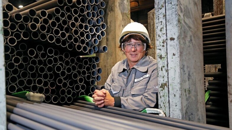 Bestens ausgerüstet: Personalchefin Katrin Pinkert lehnt in der typischen grauen Arbeitskleidung zwischen den fertigen Rohren am Ende der Produktionshalle in Zeithain. Zuvor haben die Rohre den rund 400 Meter langen Fertigungsprozess durchlaufen. Foto: Se