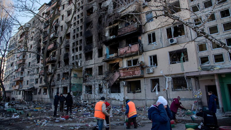 Ukrainisches Militär und Freiwillige bei Aufräumarbeiten vor einem Wohnhaus in Kiew, das von einem russischen Luftangriff getroffen wurde.