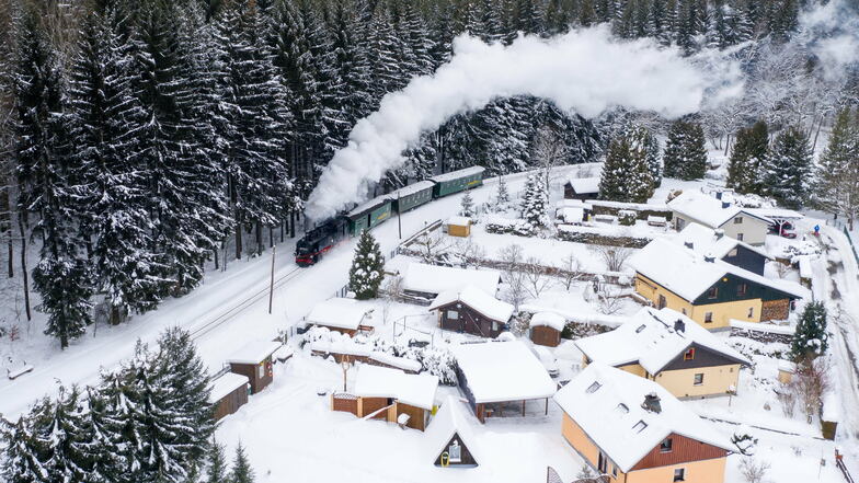 Die Fichtelbergbahn dampft durch das verschneite Erzgebirge. Den Passagieren bietet sich momentan ein wundervoller Ausblick auf verschneite Landschaft.