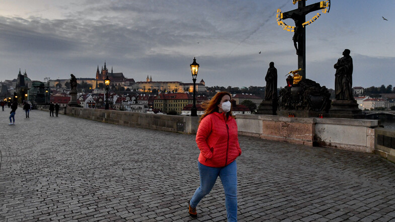 Eine Frau mit Mund-Nasen-Schutz geht über die Prager Karlsbrücke.